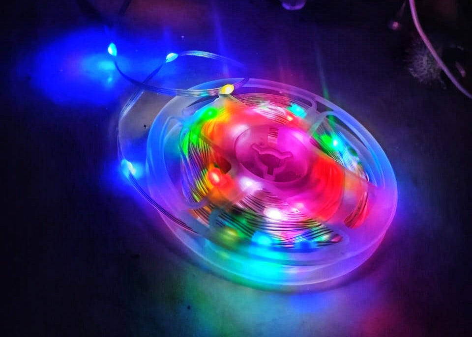 Colorful LED strip light on a dark surface with visible wires.