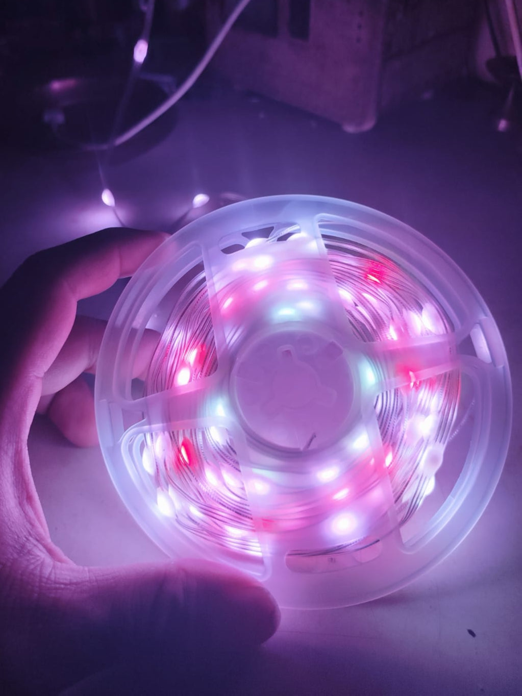 Spool of LED strip light held by a hand in a dark setting